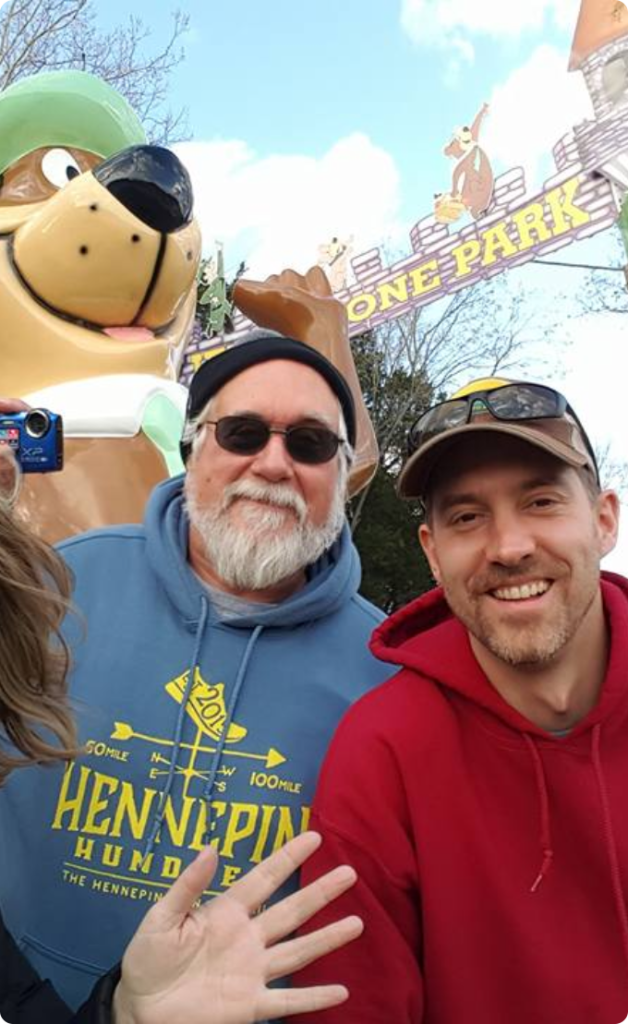 people smile for a photo in front of a large bear statue in a natural setting