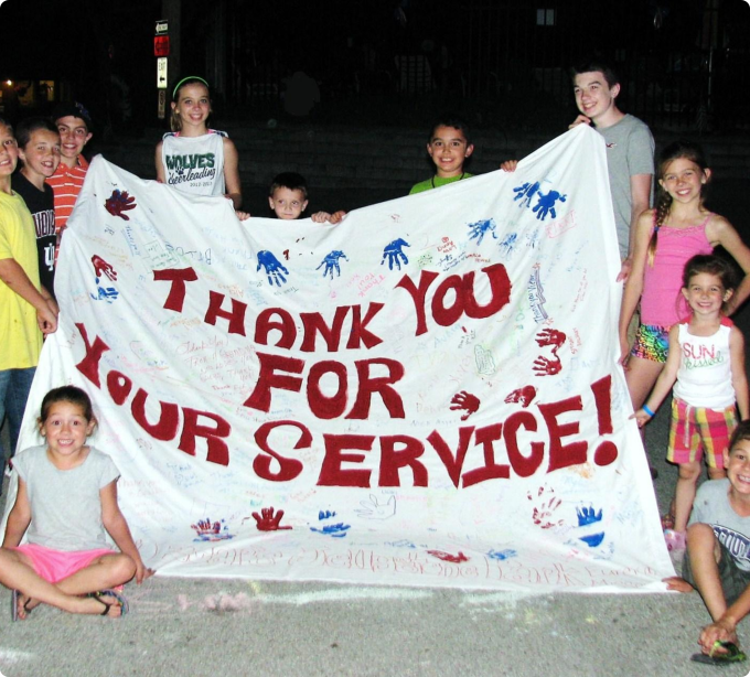 A group of children joyfully holding a colorful thank you sign