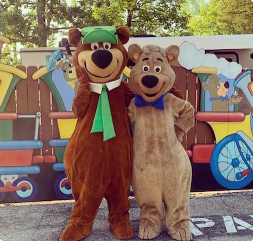 Two bears stand side by side in front of a train