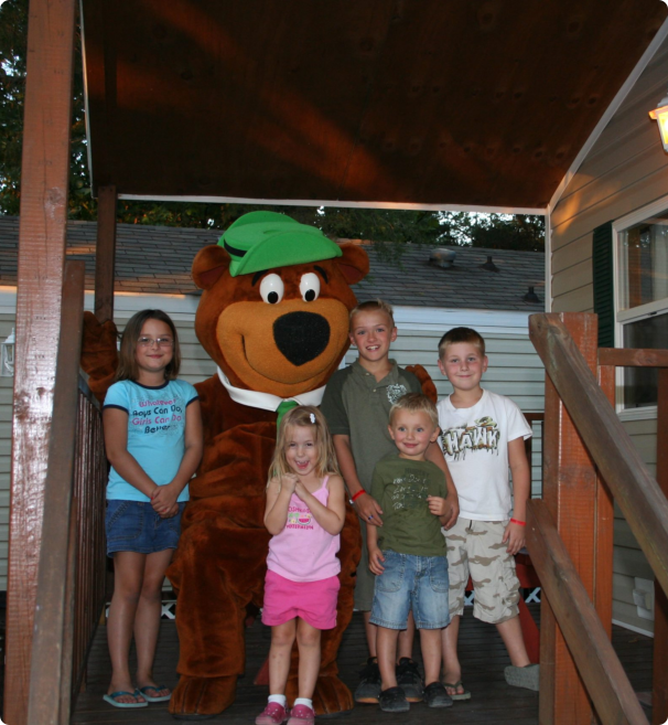 A group of children poses in front of a bear