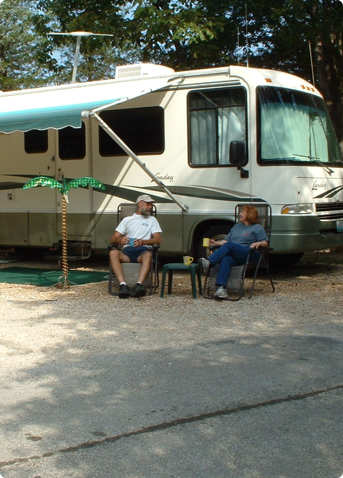 A couple of people sitting in chairs beside a motor home