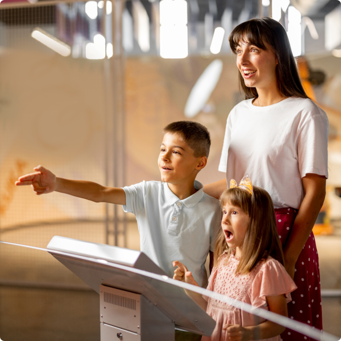 A woman and two children observe a display
