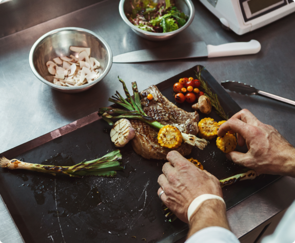 A man chops vegetables on a black cutting board